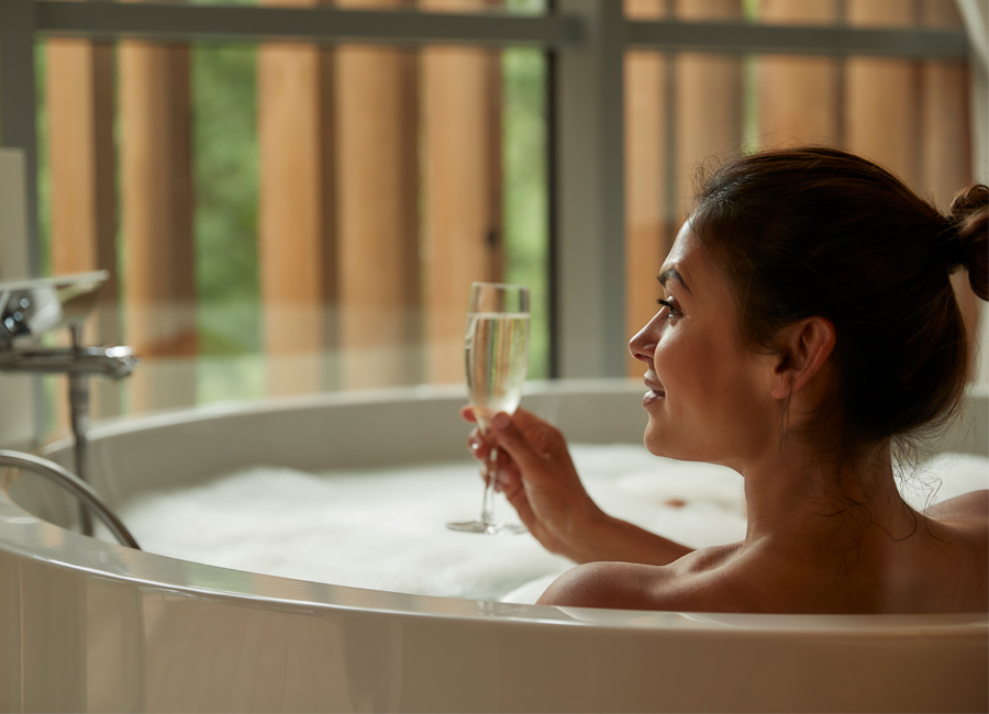 women in bath tub with glass of prosecco