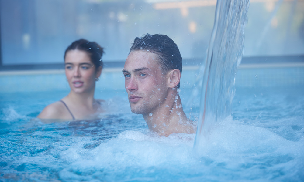 Man soaking under a flowing water fountain.
