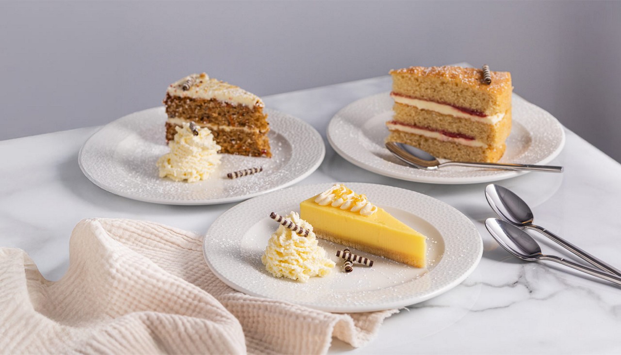 Selection of cakes including Victoria sponge, carrot cake and a lemon tart.