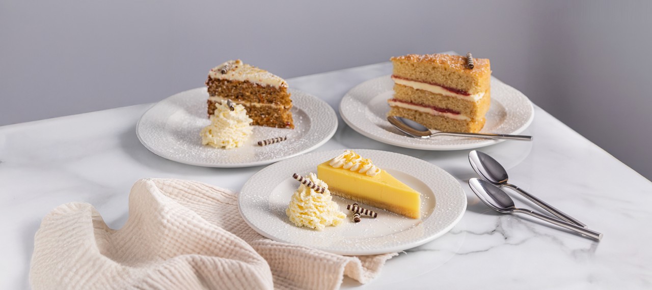 Selection of cakes including Victoria sponge, carrot cake and a lemon tart.