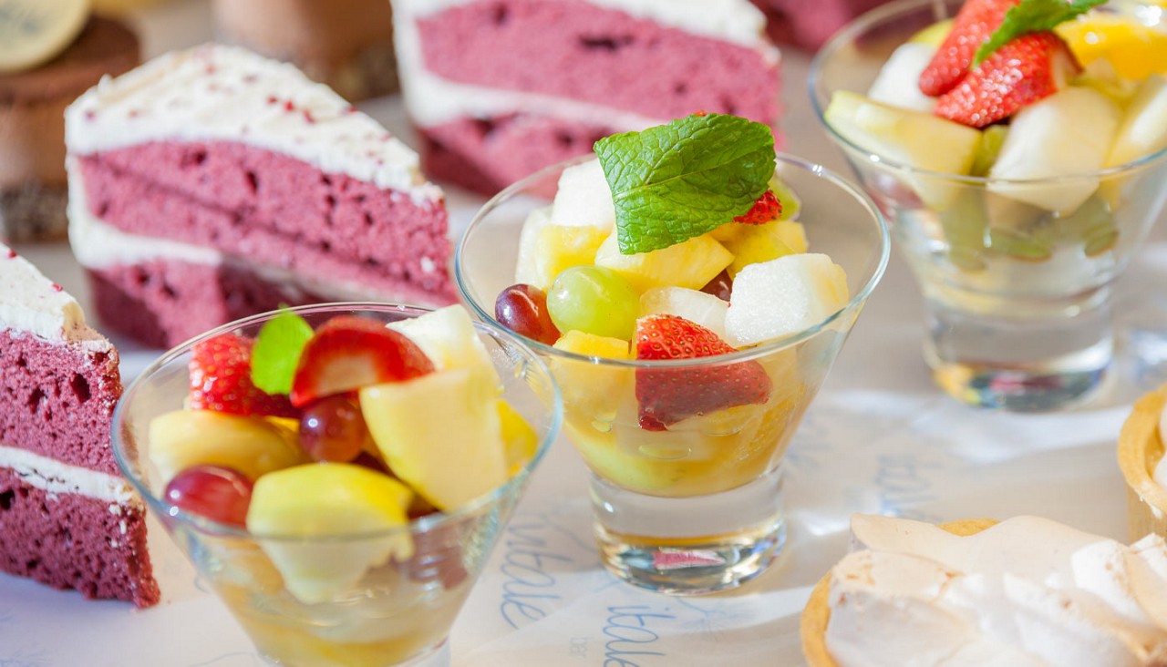 Fruit salads, cakes and tarts presented in a row.